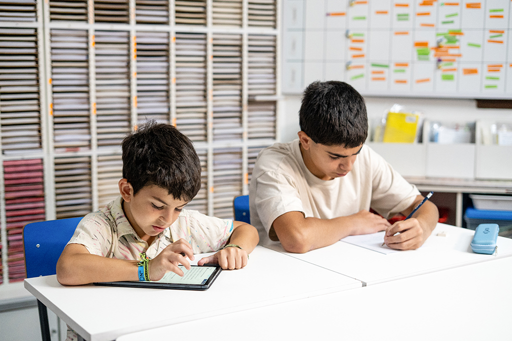 Dos estudiantes en un aula de Kumon, uno trabajando en una tableta y otro escribiendo en papel-Bolivia