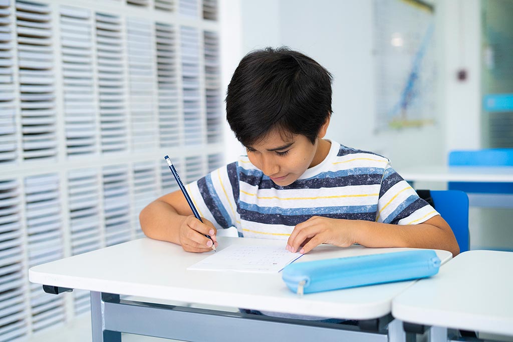 Niño concentrado resolviendo ejercicios en papel como parte del método de estudio individualizado de Kumon-Bolivia