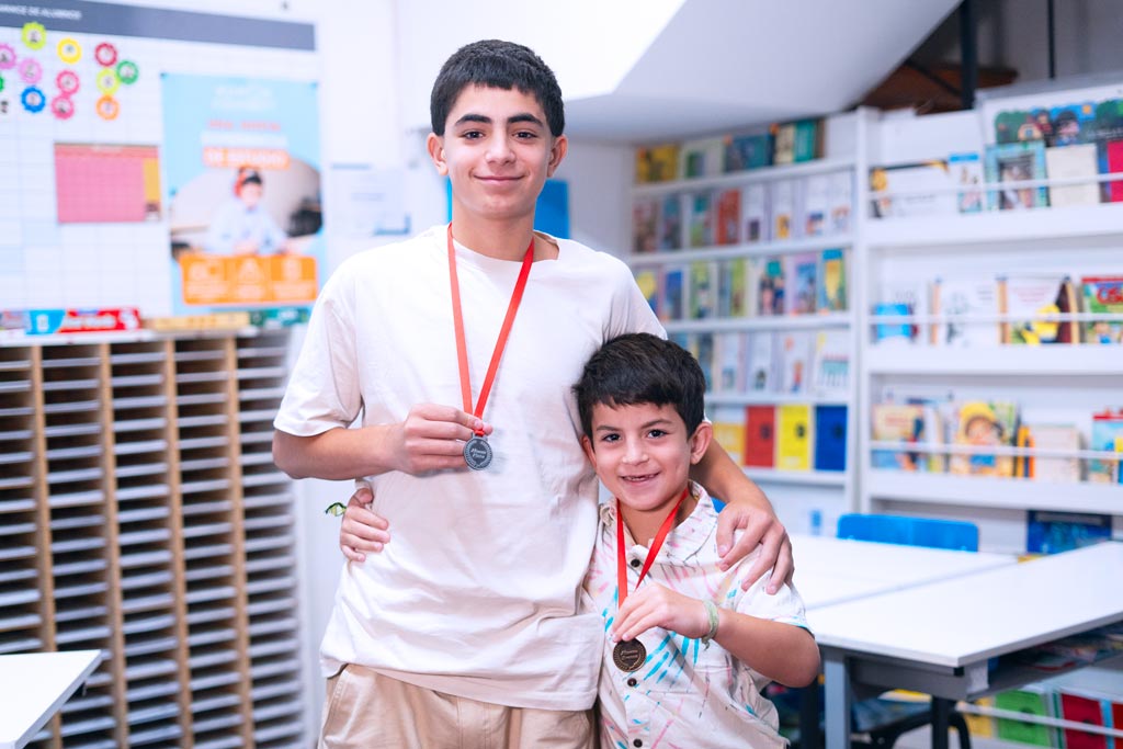 Dos estudiantes en un centro Kumon mostrando orgullosamente sus medallas por logros educativos-Bolivia