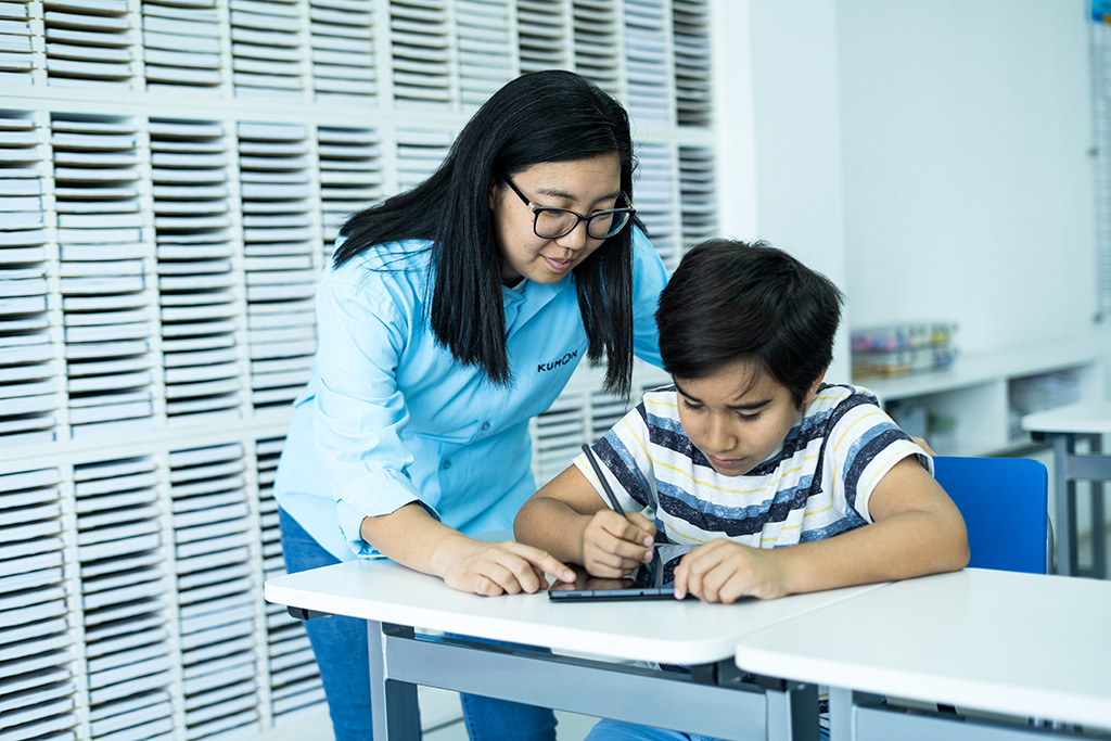 Orientador guiando a un estudiante mientras utiliza una tableta para el aprendizaje individualizado en el aula-Bolivia